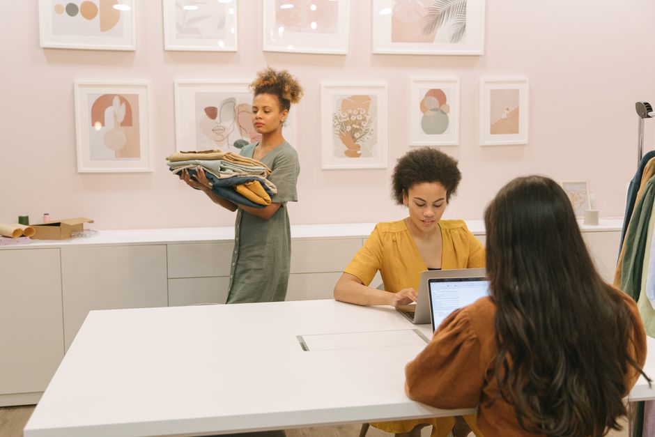 Three women working together in a stylish office setting, focusing on teamwork and clothing business.