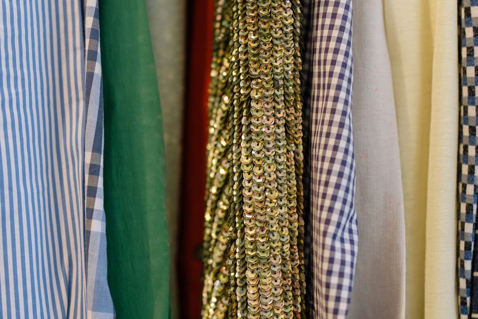 Close-up of assorted fabrics including sequined and patterned textiles on display in a retail shop.