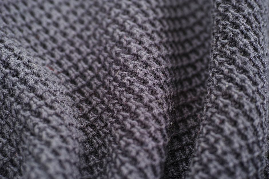 Detailed close-up photo of a gray textured woolen fabric showcasing weaving patterns.
